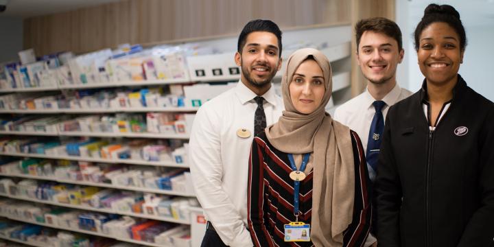 Group photo of four Boots employees in a Boots pharmacy, smiling at the camera