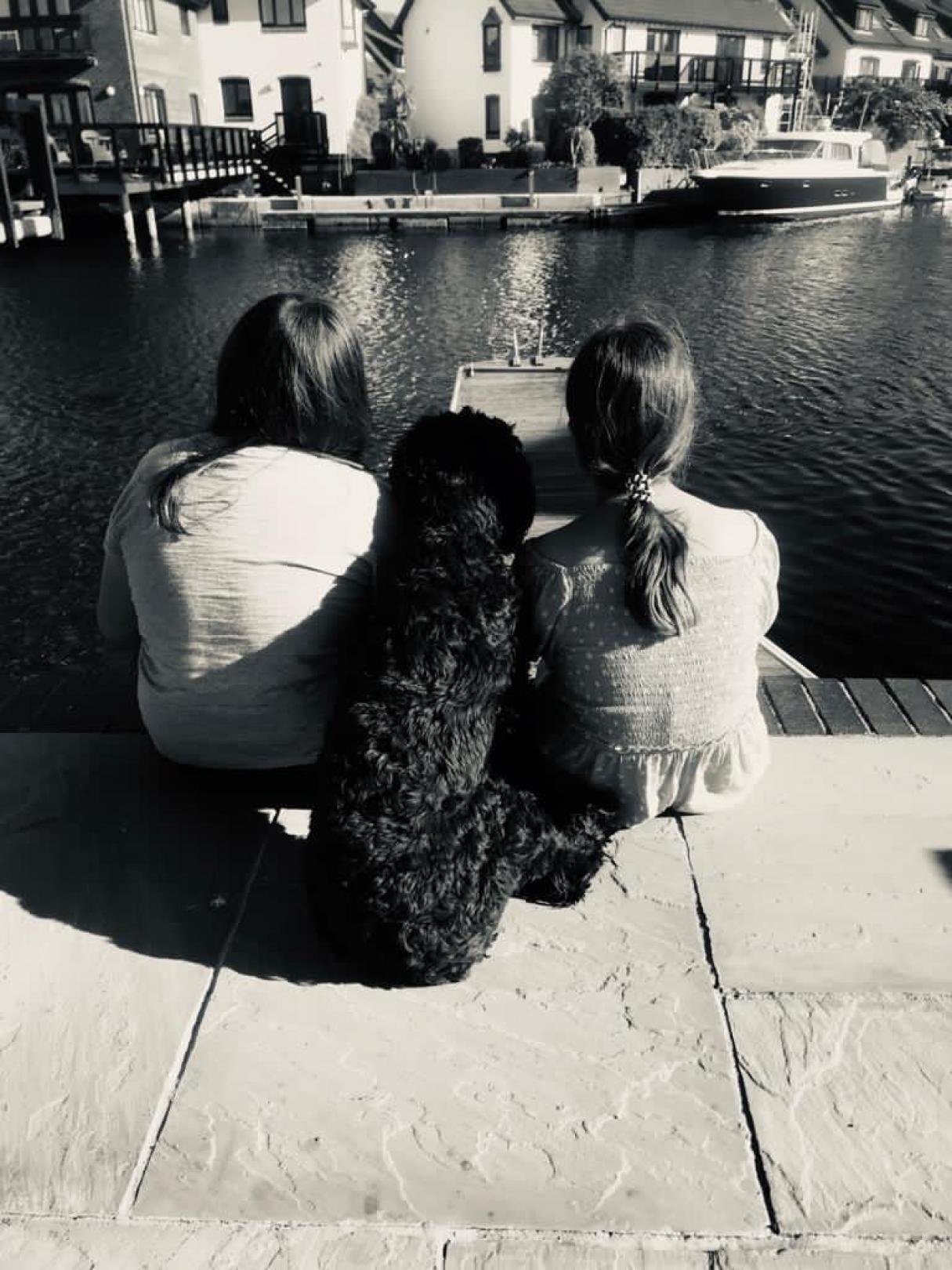 Two children and a dog staring at water 