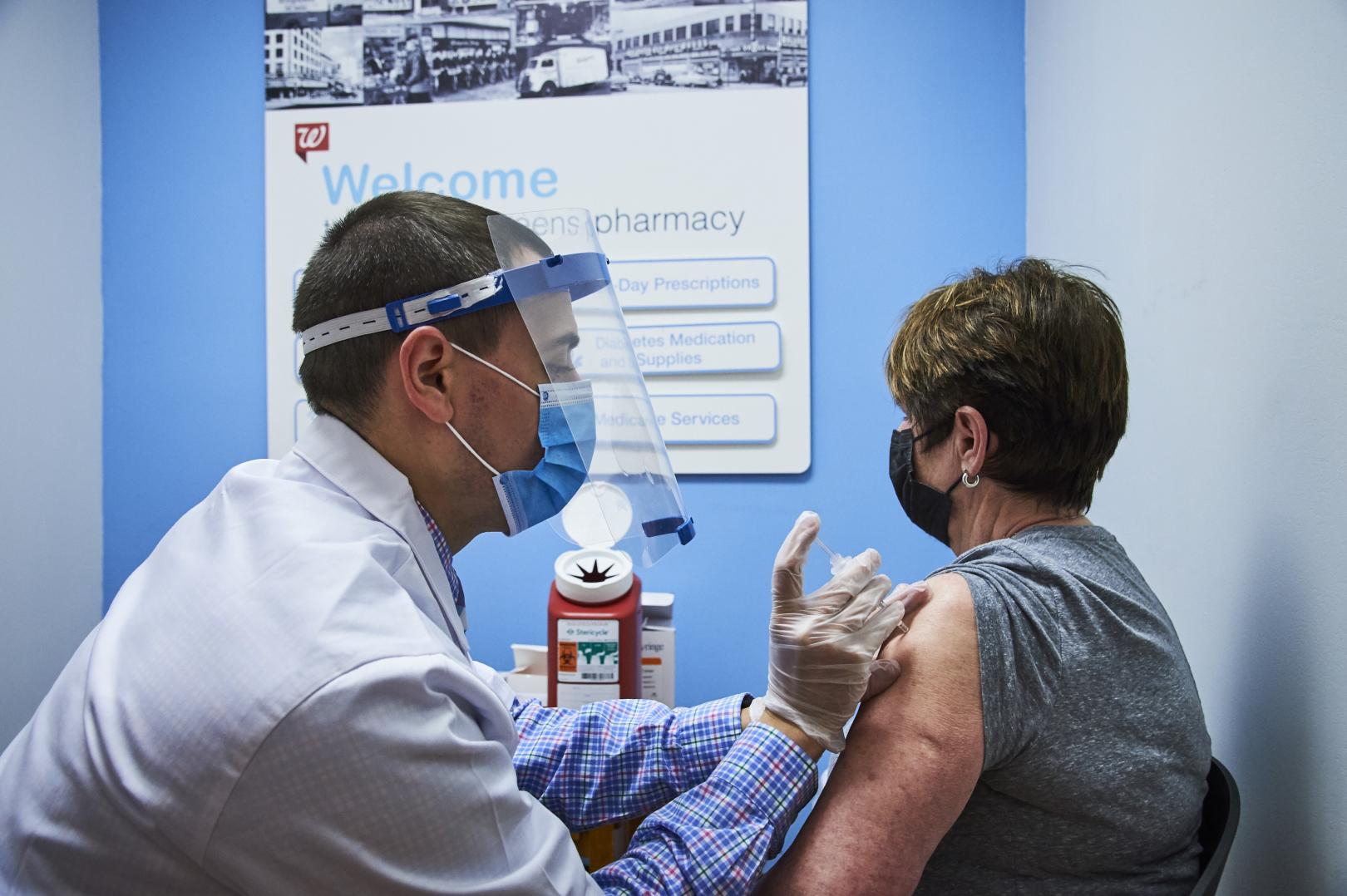 Male pharmacist administering vaccine to female patient