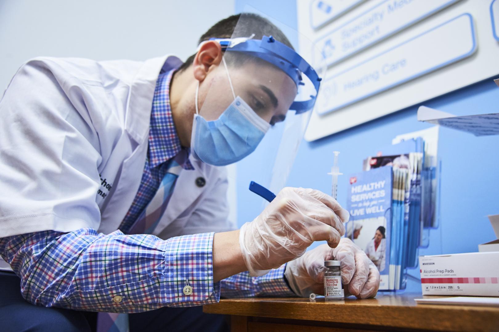 Male pharmacist filling syringe with vaccine