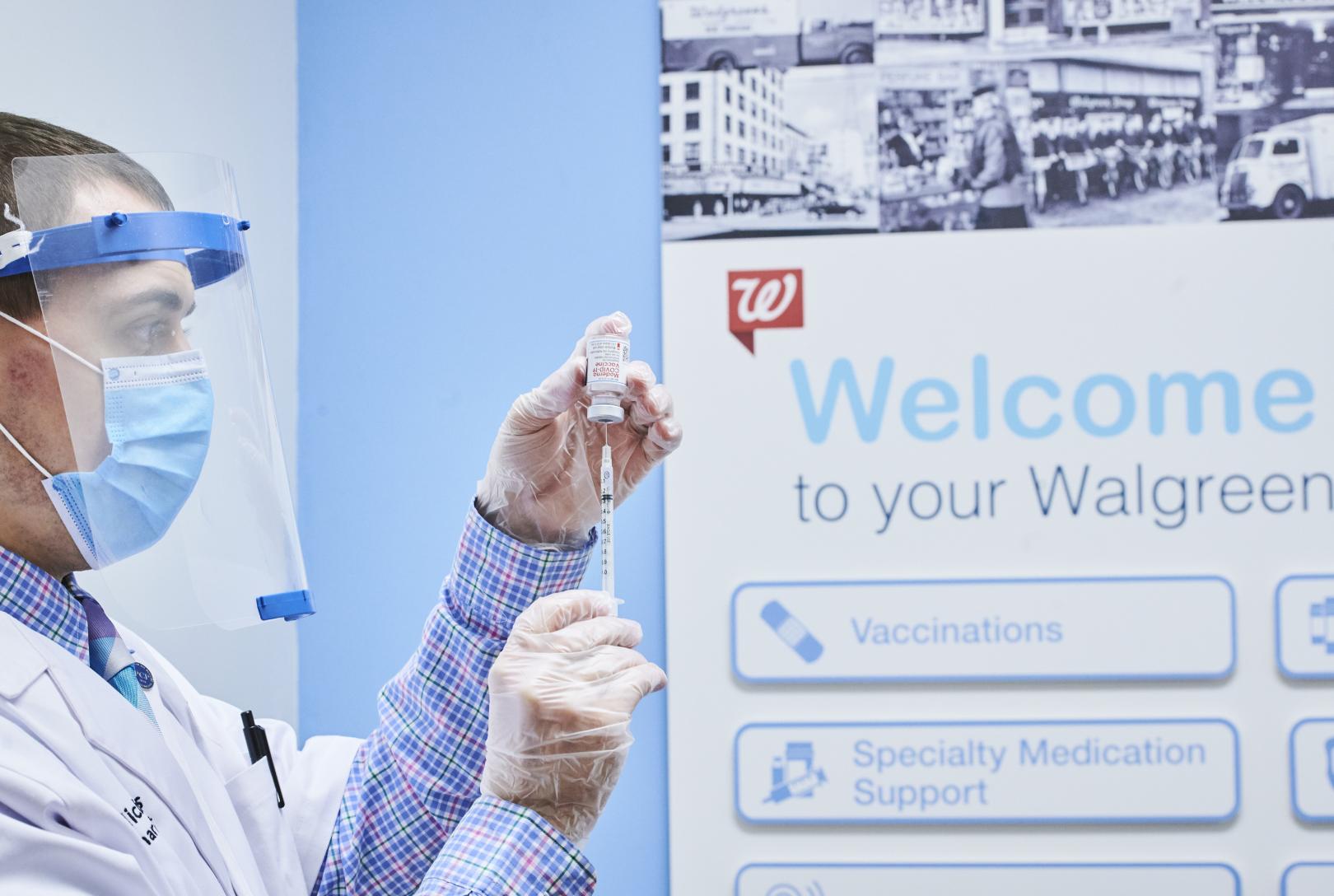 Male pharmacist filling inverted syringe with vaccine