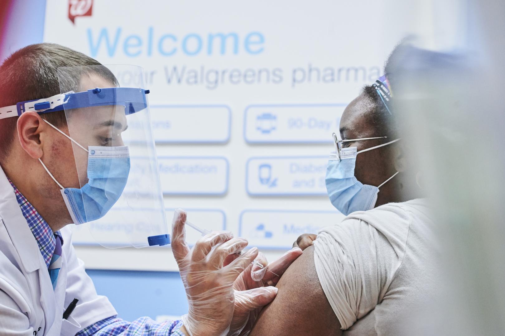 Male pharmacist administering vaccine to female pharmacist