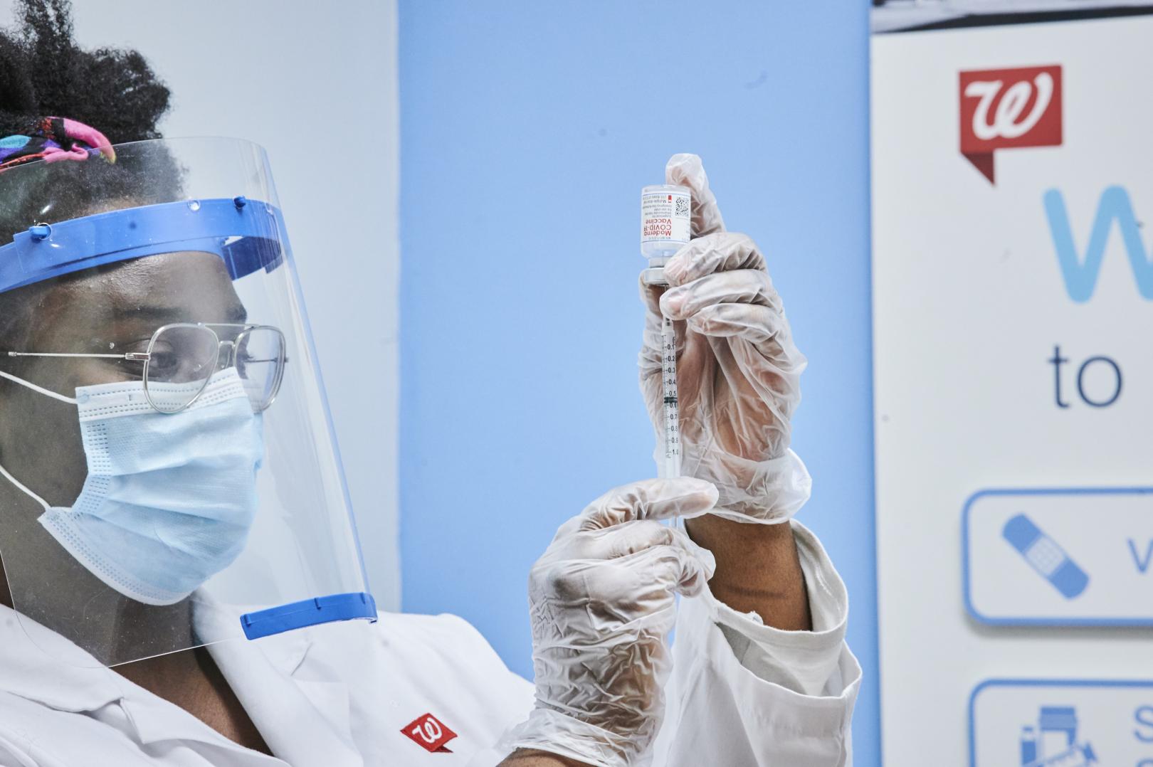 Female pharmacist filling syringe with vaccine