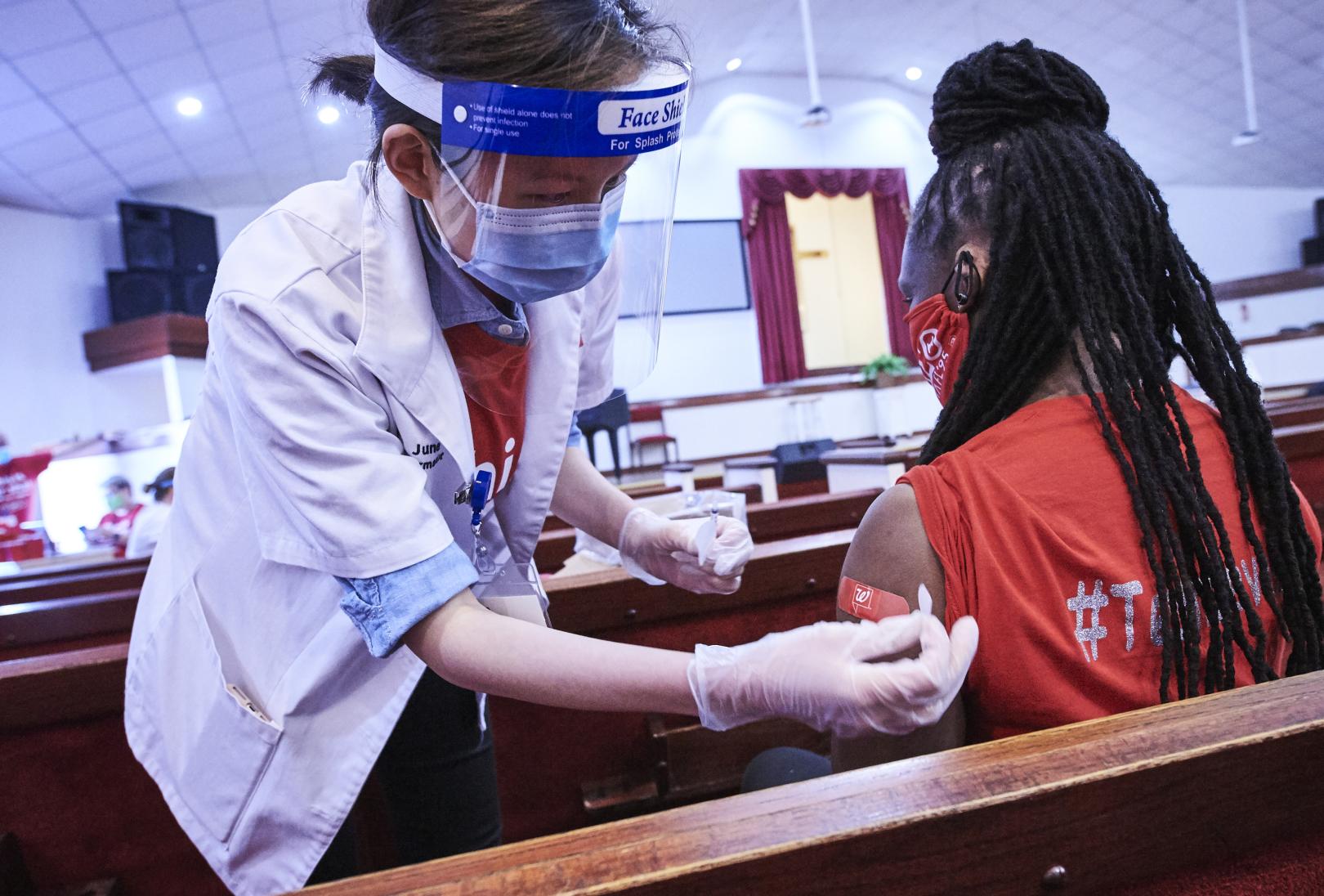 Female pharmacist with face shield applying bandage