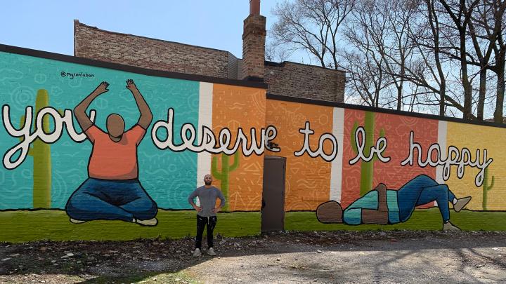 Myron standing next to one of his mural