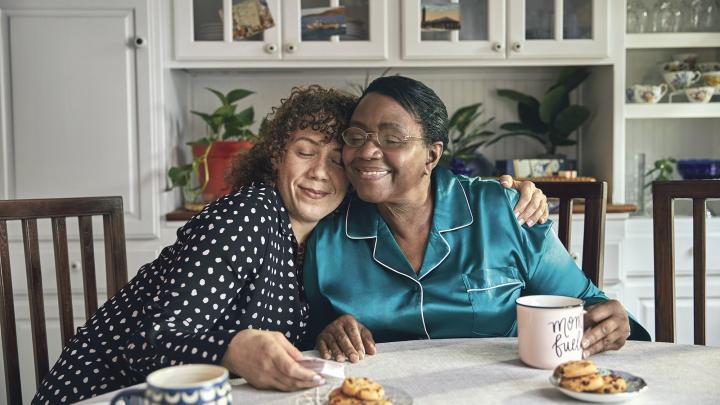 Middle aged woman side-hugging an older woman