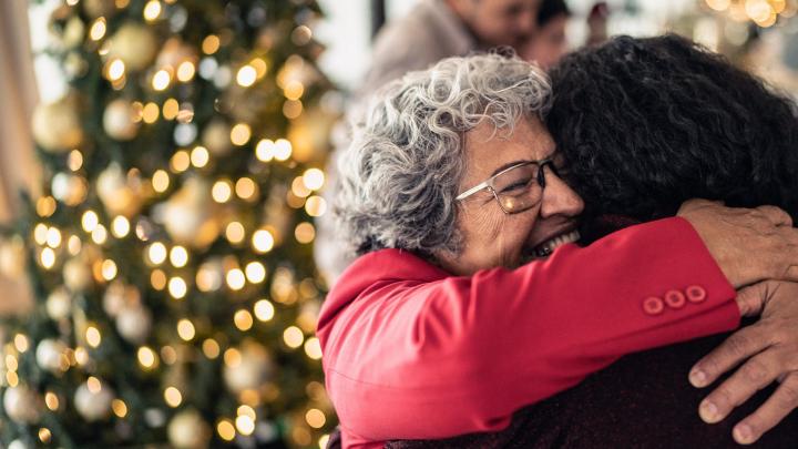 Women embracing by Christmas tree