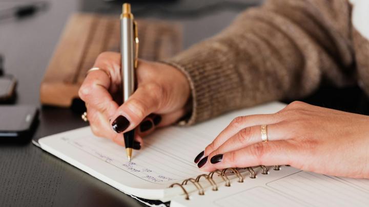 Hands on a journal, writing goals.